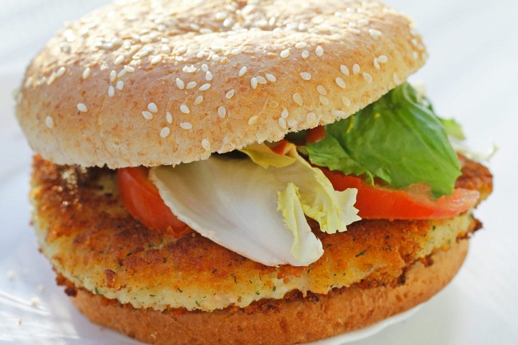 A sesame seed bun sandwich with a breaded patty, lettuce, and tomato slices.