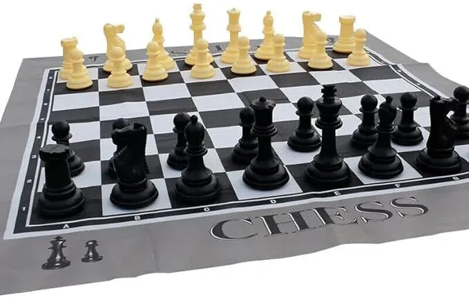 A chessboard with black and white chess pieces arranged in their starting positions on a mat labeled "CHESS.