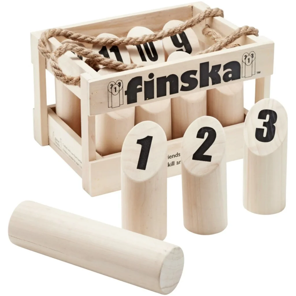 A wooden Finska game set with numbered wooden pins, a throwing pin, and a crate with a rope handle. The crate displays the "finska" logo.