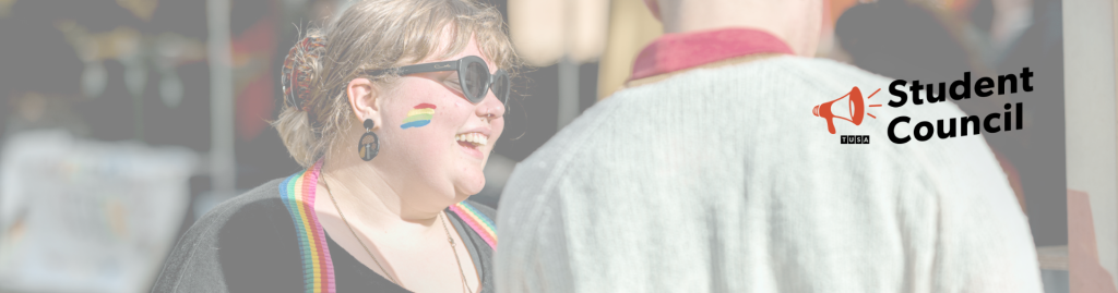 Smiling person with a rainbow painted on their cheek talks to another person; “Student Council” text and megaphone icon are on the right-hand side.